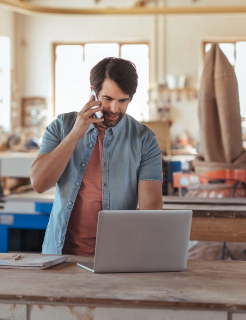 a small business owner takes a phone order in his workshop