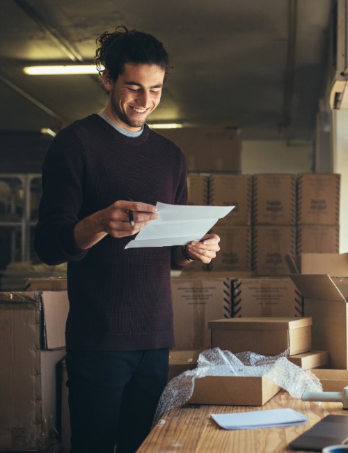 a small business owner reads a packing slip while shipping goods