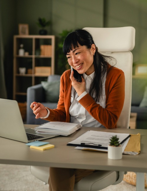 a small business owner works in a home office and speaks to a client on the telephone