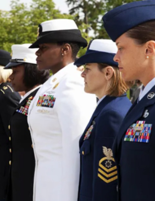 women serving in the military stand at attention in their dress uniforms